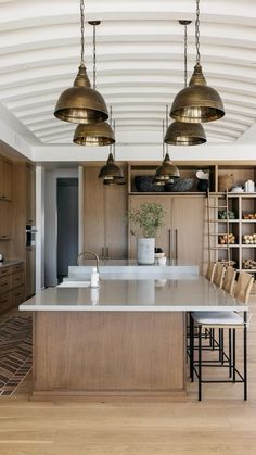 a large kitchen with wooden cabinets and gold pendant lights hanging from the ceiling over the island