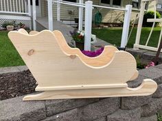 a wooden toy sleigh sitting on the side of a brick wall in front of a house