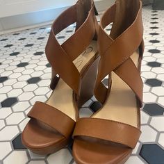 a pair of brown sandals sitting on top of a tiled floor