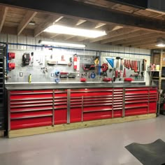 a garage with lots of tools on the wall and red cabinets in front of it