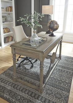 a living room with a table, chair and lamp on it in front of bookshelves