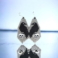 a pair of black and white beaded earrings with a bird on the front side