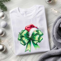 This Coquette Bow T-Shirt brings a festive and stylish vibe to your holiday wardrobe. Perfect for anyone looking to add some holiday cheer to their outfit during the Christmas season. The unisex T-shirt is made from soft and durable ring-spun cotton, making it comfortable to wear all year round. Product features - Made from 100% ring-spun cotton for a lightweight and comfortable feel - Classic fit with crew neckline for versatile styling options - Ethically grown and harvested US cotton for sust Christmas Holiday Crew Neck Shirt, Green Crew Neck Christmas Shirt, Christmas Party T-shirt With Graphic Print, Green Holiday Top For Christmas, White Winter Tops As Gift, Green Christmas Holiday Top, White Winter Tops As Gifts, White Winter Tops For Gifts, White Winter Tops As A Gift