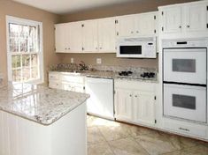 an empty kitchen with white cabinets and marble counter tops in front of a window that looks out onto the yard