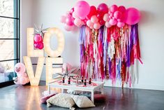 a room filled with balloons and confetti in the shape of love on display