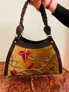 This stunning handcrafted top handle bag/shoulder bag combines genuine leather with velvet decorated with floral motifs and particular entwined handles. Handmade by skilled Kashmiri artisans, Inside it has a black lining and features two big zippered compartments, plus a small zippered compartment for valuables. You will impress with this original piece! It has crossbody straps but can be also hold in hand. The size is 38 cm length x24 cm height x 12 depth. - 100 % Genuine Natural leather A chic Elegant Handmade Satchel With Double Handle, Handmade Rectangular Velvet Bag, Handmade Velvet Rectangular Bags, Handmade Rectangular Velvet Bags, Elegant Handmade Brown Satchel, Elegant Brown Handmade Satchel, Elegant Handmade Double Handle Satchel, Handmade Velvet Bags, Festival Poncho