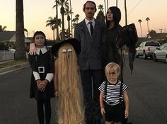 a family dressed up in costumes on the side of the road with palm trees behind them