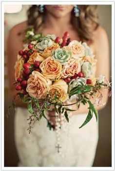 a bride holding a bouquet of roses and succulents