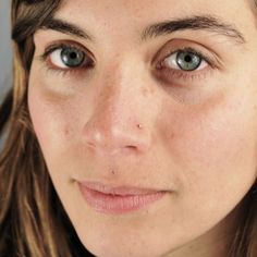 a woman with freckled hair and blue eyes looks at the camera