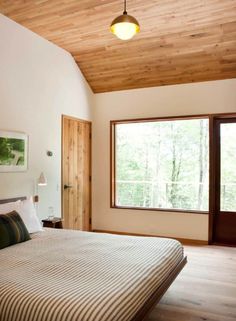 a large bed sitting in a bedroom next to a wooden ceiling mounted light above it's headboard