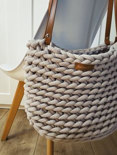 a basket sitting on top of a wooden floor next to a white chair with a brown leather handle