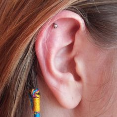 a close up of a person's ear with a colorful bead on it