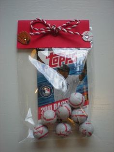 the baseballs are wrapped in plastic and tied with a red string to hang on the wall