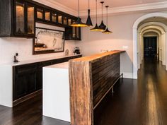 an empty kitchen with wooden floors and black cabinetry, along with pendant lights hanging from the ceiling