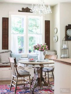 a dining room table with two chairs and a vase on top of it in front of a window