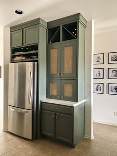 a kitchen with green cabinets and stainless steel refrigerator freezer in the center, built into the wall