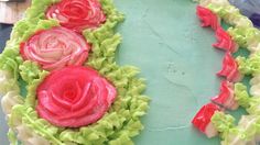 a cake decorated with flowers and icing on top of a blue table next to other items