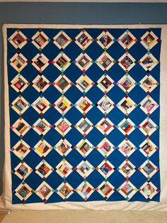 a blue and white quilt hanging on the wall