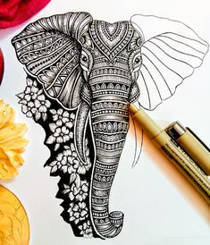 an elephant drawn in black and white on paper next to flowers, pencils and markers