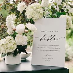 white flowers and greenery in vases on a table with a sign that says, please sign our bjc