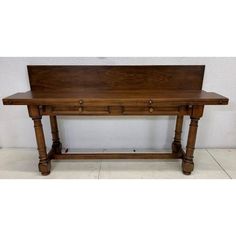 an old wooden desk with two drawers on one end and a shelf underneath it, in front of a white wall