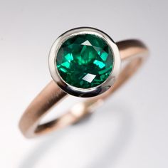 a close up of a ring with a green stone in it's center, on a white background