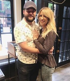 a man and woman standing next to each other in front of a storefront door