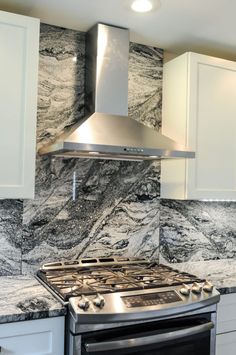 a stove top oven sitting inside of a kitchen next to white cabinets and counter tops