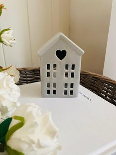 a small white house sitting on top of a table next to flowers and a basket