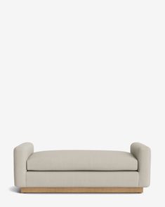 a white couch sitting on top of a wooden frame in front of a gray wall