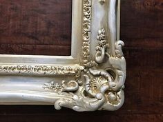 an ornate white frame on a wooden wall