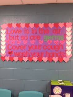 a bulletin board that says love is in the air but so are games cover your cough and wash your hands