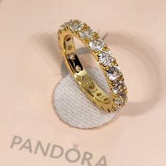 New Pandora Sparkling Row Eternity 14k Golden Plated Size 7 / 54 With Box Fast Shipping Same Day Before 3pm Central Time This Beautiful Ring From Pandora Is Perfect For Any Special Occasion, Whether It's An Engagement, Wedding, Anniversary, Or Birthday. The Ring Is Plated With 14k Golden And Features A Sparkling Row Of Stones In An Eternity Style. The Ring Is A Size 7 Or 54 And Is Made In Thailand. Gold Cubic Zirconia Eternity Band For Anniversary, Dazzling Gold Eternity Band Gift, Dazzling Gold Eternity Band For Anniversary, Gold Brilliant Cut Eternity Band As Gift, Gold Eternity Band With Brilliant Cut As Gift, Gold Eternity Band With Vs Clarity, Gold Eternity Band With Vs Clarity Round Cut, Gold Pandora Rings, Pandora Rings Gold