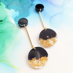 two black and gold earrings sitting on top of a table