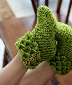 a woman's hand with green knitted mittens and buttons on her fingers