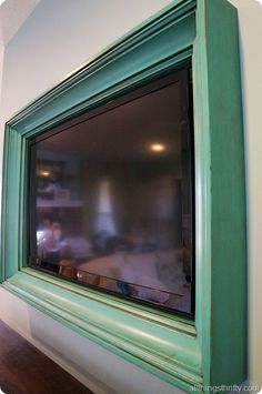 a green framed tv mounted to the side of a wall in front of a window