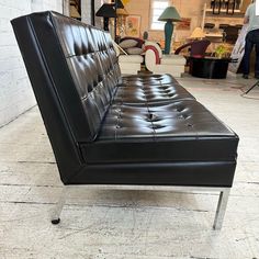 a black leather couch sitting on top of a hard wood floor next to a white brick wall