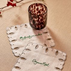 two napkins that are sitting on a table with a cup in front of them