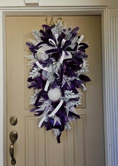 a purple and white wreath hanging on the front door