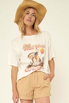 Garment washed graphic t-shirt. Vintage-style cowboy graphic with "The Wild West Cowboy" text. Torn and distressed detailing at collar, sleeves, and hem. Round neckline. Short drop-shoulder sleeves. Loose, oversized fit. 100% Cotton. Imported top designed and printed in Los Angeles, CA. Model wears size S. Vintage Summer T-shirt For Rodeo, Graphic Tee For Rodeo And Spring, Spring Graphic Tee For Rodeo, Spring Rodeo Graphic Tee, Retro Summer T-shirt For Rodeo, Retro Summer Rodeo T-shirt, Casual Distressed Tops For Rodeo, Oversized Tops For Rodeo In Spring, Trendy Relaxed Fit T-shirt For Rodeo