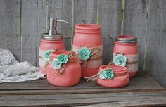 four mason jars with flowers on them are sitting on a wooden table next to a lace doily