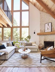 a living room filled with lots of furniture next to a fire place and large windows