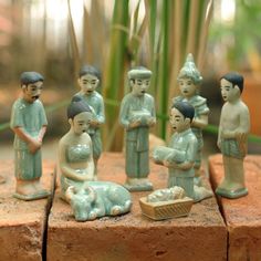 a group of figurines sitting on top of a brick wall next to bamboo plants