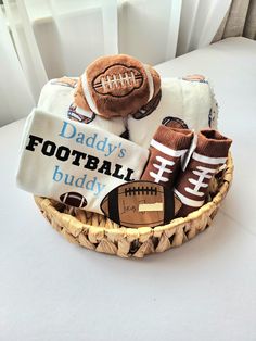 a basket filled with baby's football items on top of a white tablecloth