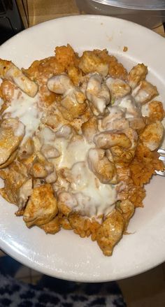 a white plate topped with chicken and cheese covered in gravy on top of a table