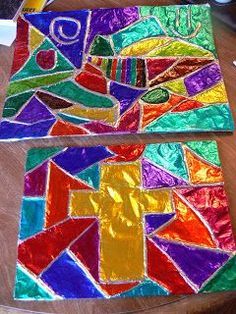 two pieces of stained glass sitting on top of a wooden table