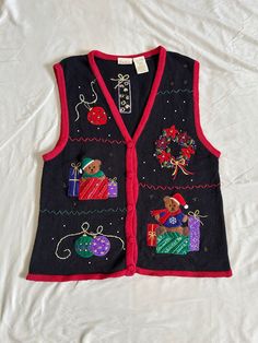 a black vest with red trimmings and teddy bears on it, sitting on a white sheet