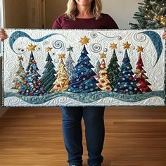 a woman is holding up a quilted christmas tree banner with stars and swirls