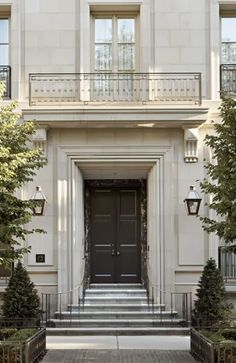 an entrance to a large white building with two black doors and steps leading up to it