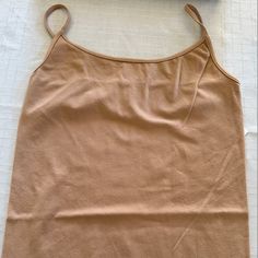 A Basic Camisole Featuring A Round Neckline And Form-Fitting Silhouette. One Size Color: Sand Beige Model Is To Show Fit, Not Color Made In Usa Fabric: 92% Nylon / 8% Spandex Solid Color Cami Top With Built-in Bra, Beige Sleeveless Tank Top With Built-in Bra, Beige Cotton Tank Top With Built-in Bra, Solid Color Tops With Built-in Bra And Wide Straps, Beige Stretch Tank Vest, Beige Stretch Vest Top, Beige Stretch Cami Tank Top, Beige Stretch Top With Built-in Bra, Fitted Seamless Vest With Tank Straps